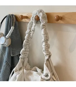 Detail der cremefarbenen Cord-Umhängetasche mit gerafftem Riemen an einem Holzhaken
