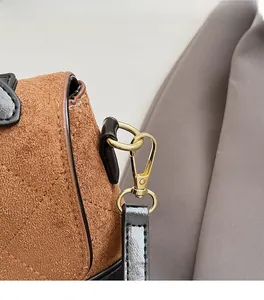 Détail macro du fermoir doré et texture en daim matelassé sur un sac bandoulière marron