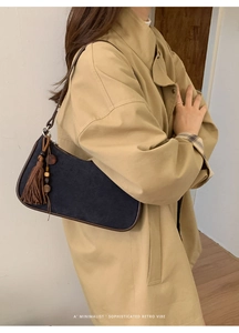 Close-up of retro suede crossbody bag with brown tassel and wooden bead charm detail