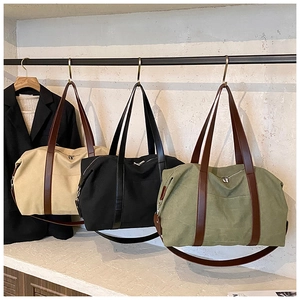Detailed shot of large canvas tote bags in beige, black and olive green with leather handles