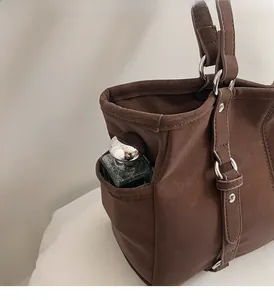 Detail of the vintage dark brown tote bag showing a side pocket for perfume storage