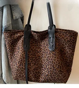 Vue détaillée du sac cabas en suédine léopard avec des anses renforcées en cuir noir