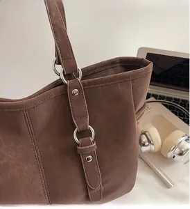 Detail of premium silver buckles and textured dark brown leather tote on a stylish office desk