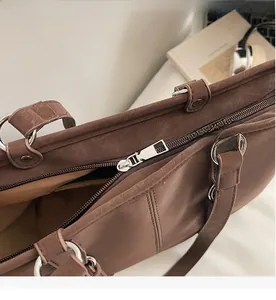 Detail of smooth metal zipper and premium suede texture on a brown tote bag