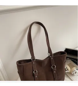 Detail of brown faux leather tote with reinforced long straps and silver rivet accents