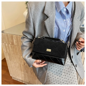 Détails du sac à bandoulière noir matelassé mêlant textures en daim mat et cuir brillant