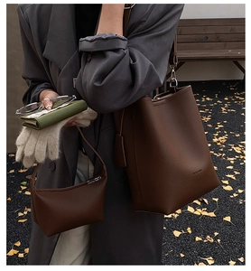 Detail view of large brown leather bucket bag and small hobo bag in autumn setting