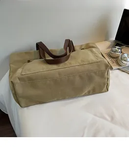 Detail of durable khaki canvas tote bag with premium brown leather handles and stitching