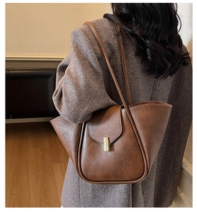 Close-up of vintage brown leather tote bag with unique curved edge and metal buckle