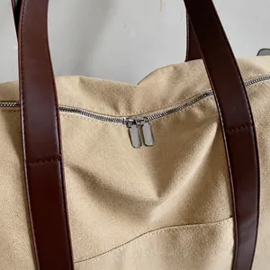 Detalle de bolso tote de lona vintage con cremallera metálica y asa de cuero marrón