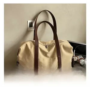 Detailed macro view of large canvas travel tote bag featuring brown leather trim and zipper