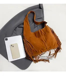 Detail showing the large storage capacity of a brown suede tassel hobo bag next to gadgets