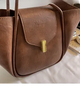 Detail of premium brown textured leather bag with polished gold metal clasp hardware