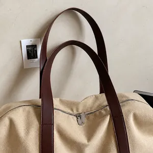 Detalle del bolso tote de lona con asas de cuero y cierre de cremallera metálica de calidad