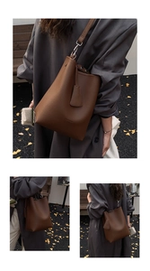 Detail of a brown leather bucket bag with HOCOMU logo on textured pebble leather finish