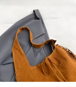 Close-up of brown suede tote bag featuring wide handle and stylish side fringe detail