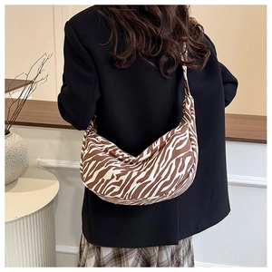Detailweergave van een vrouw die een schoudertas met zebraprint draagt op een zwarte blazer