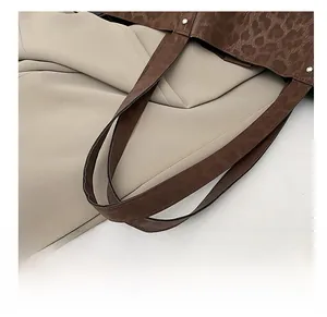 Detail of leopard print tote bag featuring metallic rivets and sturdy brown handle