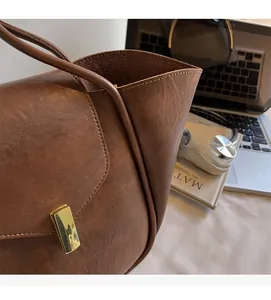 Close-up of brown faux leather bag featuring a gold rectangular buckle and matte texture