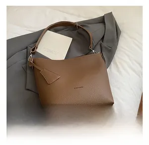 Detail of dark brown lychee grain leather bucket bag on grey suit fabric background