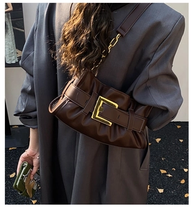 Detail of retro dark brown pleated bag with large gold square buckle and chain strap