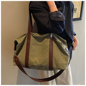 Olive canvas tote bag with brown leather handles worn over the shoulder by a model