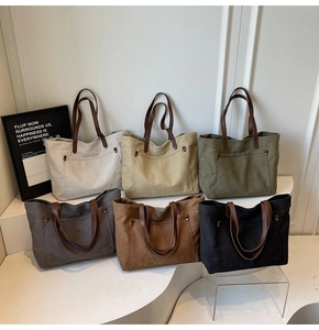 Detailed view of large canvas tote bags in six colors with leather handles on a minimal display