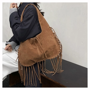 Detail of a brown suede tote bag featuring long fringes and handmade woven stitching