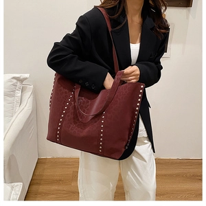 Close-up of burgundy leopard print tote bag featuring silver rivet hardware and straps
