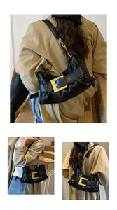 Detail of black pleated shoulder bag featuring a large gold square buckle and chain strap