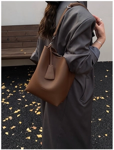Close-up of brown pebbled leather bucket bag with brand logo and minimalist shoulder strap