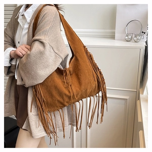 Close-up of brown suede hobo tote featuring long flowing tassels and boho details