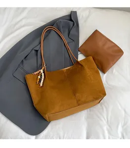 Close-up of caramel faux suede tote bag set with wooden bead charm and small pouch