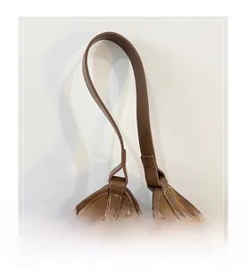 Detail of the brown leather shoulder strap with visible stitching and metal ring buckle