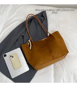 Size comparison of large brown suede tote bag with mobile phone and tablet accessories