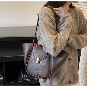 Detail of dark brown tote bag with oily texture finish and elegant gold metal clasp closure