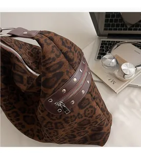 Detail of leopard print tote bag featuring smooth metal zippers and studded leather accents