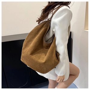Detail of deep brown suede tote bag showing large capacity and soft texture on model