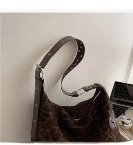 Close-up of leopard print hobo bag with wide leather grommet strap and metal buckle
