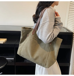 Detail of olive green canvas tote bag with brown leather handles and side rivet pocket