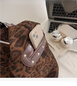 Detail of leopard print tote bag showing external zipper pocket with metal studs