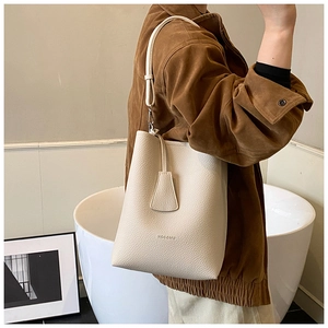 Gros plan du sac seau en cuir grainé crème avec logo HOGOMU et fine bandoulière réglable