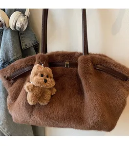 Dettaglio borsa tote in pelliccia sintetica marrone con manici in pelle e ciondolo orsetto