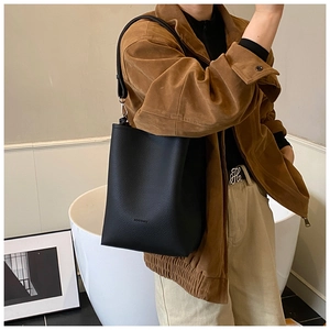 Détail du sac cabas en cuir grainé noir montrant la texture et le logo de la marque