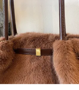 Dettaglio di borsa marrone in pelliccia sintetica con cinturini in pelle e fibbie oro