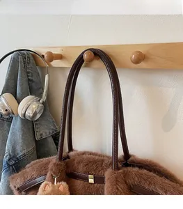 Dettaglio della borsa in peluche marrone con tracolla in pelle e ciondolo a orecchie di gatto
