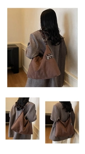 Detail view of large brown suede hobo bag with wide shoulder strap and metal rivets