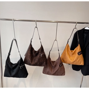 Detail of suede leopard print tote bags in four colors hanging on a display rack