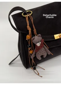 Detail of dark brown lychee grain leather bag with a removable plush bear charm