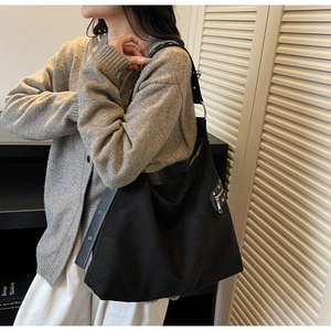 Large black hobo shoulder bag with silver zipper and wide grommet strap on a model